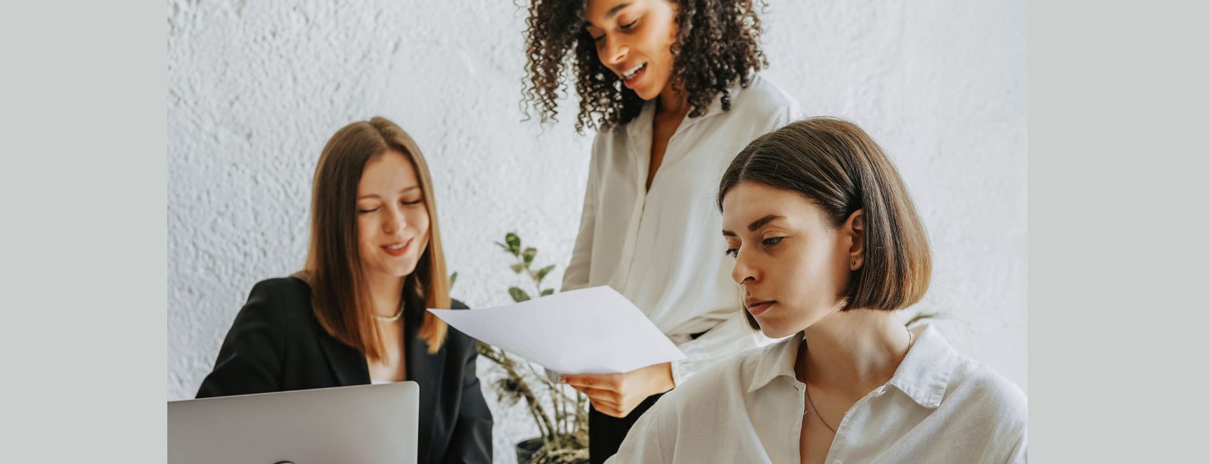 Three professional women collaborating on brand strategy planning in a modern office setting